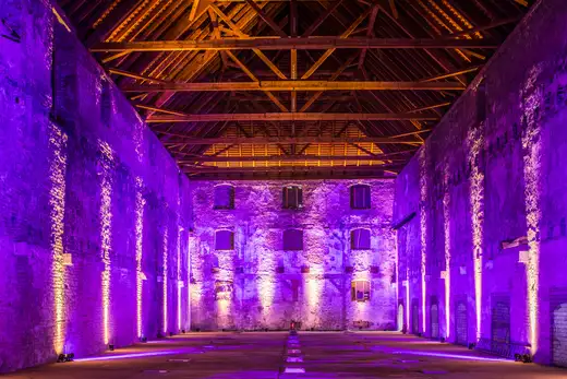 Große historische Halle mit sichtbarer Dachkonstruktion und Lichtinszenierung